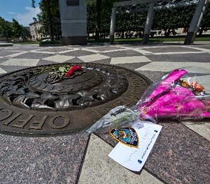 In this July 8, 2016 file photo, five red roses on the bronze medallion with another bouquet of flowers and a note in support of the Dallas Police Department are seen at The National Law Enforcement Officers Memorial in Washington.