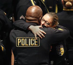 DART police officer Misty McBride, right, is embraced by a fellow officer as she arrives for a memorial at the Morton H. Meyerson Symphony Center, Tuesday, July 12, 2016, in Dallas. Five police officers were killed and several injured, including McBride, during a shooting in downtown Dallas last Thursday night. (AP Photo/Eric Gay)