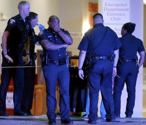 A Dallas police officer covers his face as he stands with others outside the emergency room at Baylor University Medical Center, Friday. (AP Photo/Tony Gutierrez)