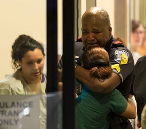 A Dallas Area Rapid Transit police officer receives comfort at the Baylor University Hospital emergency room entrance Thursday, July 7, 2016, in Dallas. Police say one rapid-transit officer has been killed and three injured when gunfire erupted during a protest in downtown Dallas over recent fatal shootings by police in Louisiana and Minnesota. (Ting Shen/The Dallas Morning News via AP)
