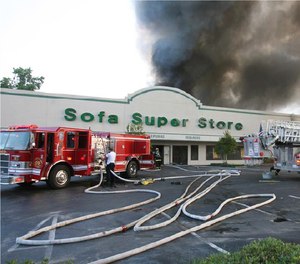 Griffin stands at the pump panel on June 18, 2007. Assistant Engineer Michael “Frenchie” French was with Ladder 5 at right.
