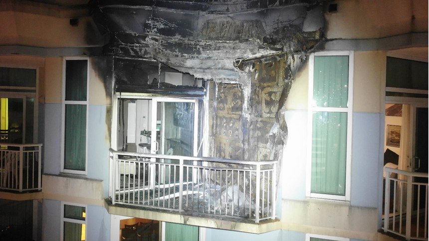 A drone shines a spotlight on a top floor of a high-rise fire.
