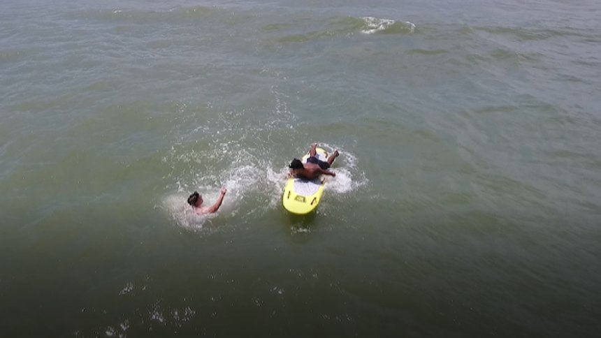 A drone hovers over an ocean rescue.