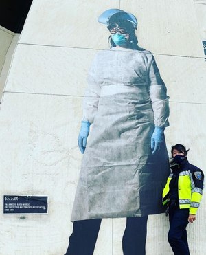 President of the Austin EMS Association, Capt. Selena Xie stands next to a large image of herself on a wall near a local hospital during EMS Week.