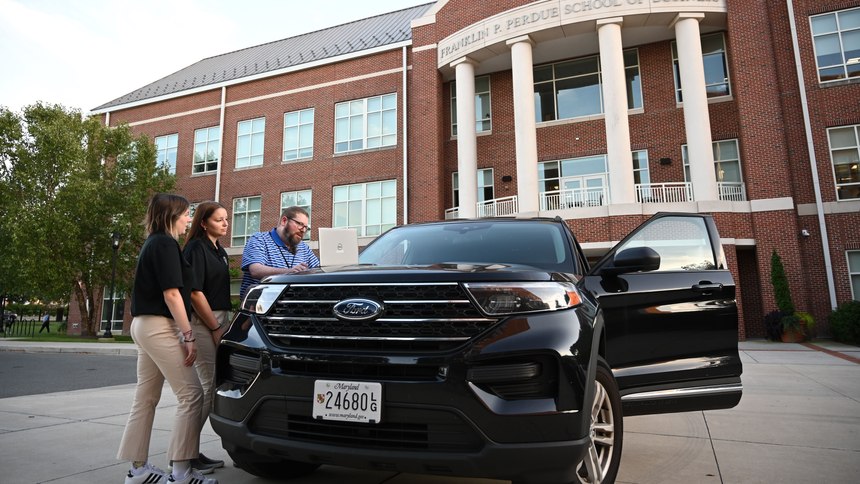 Dr. David P. Weber and Intern Investigators Samantha Schorr and Jessica McRobie working with their U.S. government-funded laptops and Ford Interceptor outside the Perdue School of Business.