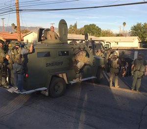 Law enforcement officials with armored vehicles search an area near where police stopped a suspect SUV in San Bernardino, Calif., Wednesday, Dec. 2, 2015.