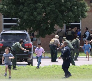 Law enforcement officials evacuate children from Robb Elementary School after a gunman killed 19 students and two teachers on March 24, 2022 in Uvalde, Texas.