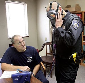Alton, Ill., Fire Department engineer Bob Eichen, left, uses a machine to run a series of five tests on the gas mask of Alton Police officer Michael Beaber, right, at the Don Twichell Memorial Fire Station in Alton. (AP Photo/The Telegraph, John Badman)