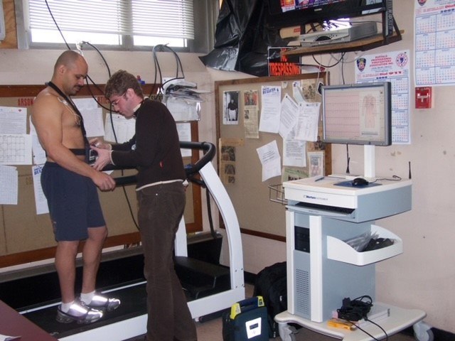 A nurse scientist applies a 12-lead electrode to measure a career firefighter's electrocardiogram during a physical test.