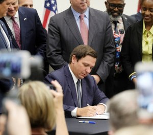 Florida Gov. Ron DeSantis signs the Sanctuary City bill Friday, June 14, 2019 at the Okaloosa County, Fla., Commission Chambers in Shalimar Fla. (Michael Snyder/Northwest Florida Daily News via AP)