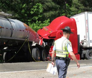 A Georgia state trooper works the scene of a deadly crash in which five people died and three others were injured early Wednesday, April 22, 2015, in Ellabelle, Ga., west of Savannah. The Georgia State Patrol said seven total vehicles, including two tractor trailers, were involved in the early morning collision on Interstate 16 about 20 miles west of Savannah. (AP Photo/Russ Bynum)