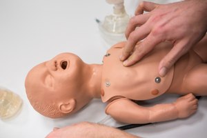 An adult demonstrates who CPR is performed on an infant.