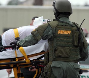 A SWAT Team paramedic treats a suspect that was brought down after taking his wife hostage in the middle of a busy roadway in Florida. (Photo/Getty Images)