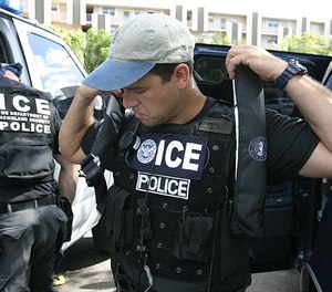 An unidentified Immigrations and Customs Enforcement agent puts on a vest in Tallahassee, Fla. The state is poised to deputize state correctional officers as agents.