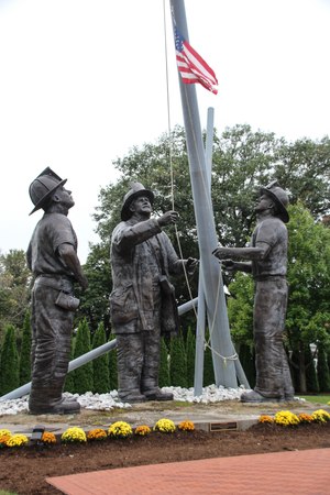 A 40-foot-tall bronze monument, named “To Lift a Nation,” was created by sculptor Stan Watts to honor the firefighters who died on September 11, 2001. The monument recreates the famous photo taken by Thomas E. Franklin, a photographer for the Bergen Record, who captured the image of three firefighters raising the American flag at Ground Zero. Along with the National Fallen Firefighters Memorial, the statue is located on the campus of the National Emergency Training Center in Emmitsburg, Maryland.