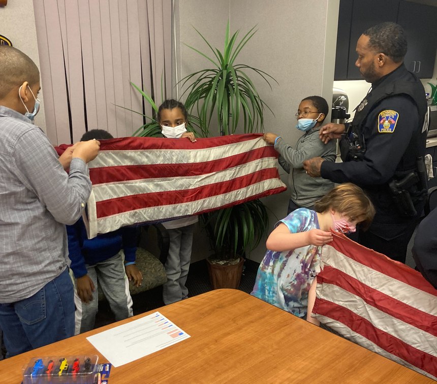 RHPD officers demonstrate flag-folding to Cop Scout participants.