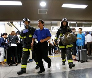 A passenger is escorted by firefighters after getting off a high-speed bullet train where a man set himself of fire, at Odawara station in Odawara, west of Tokyo, Tuesday. (AP Photo/Shizuo Kambayashi)
