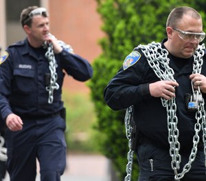 Baltimore Police carry chains that protesters had used during a monthlong sit-in at Garland Hall on Johns Hopkins' Homewood campus, Wednesday, May 8, 2019. (Jerry Jackson/The Baltimore Sun via AP)