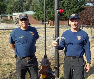 Lt. John Creel (left) and Scott Freeman (right) stand next to an installed Hydrant Snorkel.
