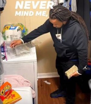 In a screen grab taken from a Facebook video, a man identified in court documents as Joseph Banks of Charlotte poses with a large amount of cash and marijuana in a laundry room.