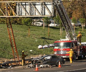 LA firefighters remove the body of a 20-year-old man who landed on a freeway sign after he was ejected from a vehicle during a fatal crash. (Al Seib/Los Angeles Times/TNS)