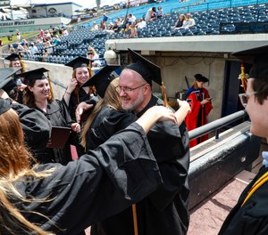 Michael Duthler is surrounded by fellow students who want to congratulate him after receiving their diplomas during the Calvin University Class of 2020 Commencement at LMCU Ballpark in Comstock Park, Michigan on Saturday, May 22, 2021.