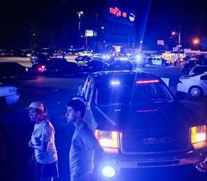 Bystanders look on as emergency personnel respond to the scene of a deadly shooting at the Grand Theatre in Lafayette (La.).