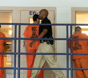 A corrections officer walks past inmates at the Metropolitan Detention Center in Albuquerque, New Mexico.