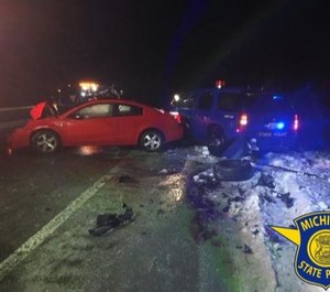 While the trooper was helping the motorist, a passing car hit his cruiser, forcing it into the trooper and motorist (Photo / Michigan State Police)