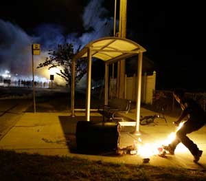 A man with a Molotov Cocktail prepares to throw it at a line of police officers in the distance in Ferguson (Mo.) during rioting in August 2014.