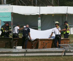 Police and fire officials hold up a sheet a body following a fatal tent collapse at the Prairie Fest in Wood Dale, Ill., Sunday, Aug. 2, 2015. Several people were injured after the tent collapsed at the festival in suburban Chicago, according to the Chicago Tribune. (Stacey Wescott/Chicago Tribune via AP)