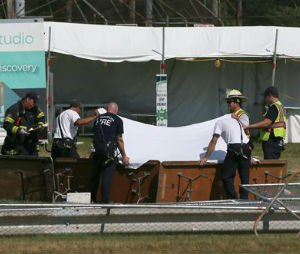 Police and fire officials hold up a sheet a body following a fatal tent collapse at the Prairie Fest in Wood Dale, Ill., Sunday, Aug. 2, 2015. Several people were injured after the tent collapsed at the festival in suburban Chicago, according to the Chicago Tribune. (Stacey Wescott/Chicago Tribune via AP)

