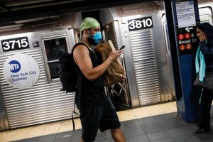 A commuter wears a face mask in the New York City transit system. Image: AP Photo/John Minchillo