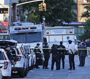 Emergency personnel stand near the scene where a police officer was fatally shot while sitting in a marked vehicle in the Bronx section of New York, Wednesday, July 5, 2017. Police said Officer Miosotis Familia died at a hospital early Wednesday. (AP Photo/Seth Wenig)