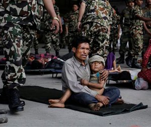 A man sits with a child on his lap as victims of Saturday’s earthquake, wait for ambulances after being evacuated at the airport in Kathmandu, Nepal, Monday, April 27, 2015. The death toll from Nepal's earthquake is expected to rise depended largely on the condition of vulnerable mountain villages that rescue workers were still struggling to reach two days after the disaster. (AP Photo/Altaf Qadri)
