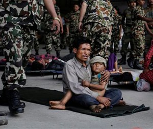 A man sits with a child on his lap as victims of Saturday’s earthquake, wait for ambulances after being evacuated at the airport in Kathmandu, Nepal, Monday, April 27, 2015. The death toll from Nepal's earthquake is expected to rise depended largely on the condition of vulnerable mountain villages that rescue workers were still struggling to reach two days after the disaster. (AP Photo/Altaf Qadri)