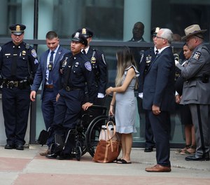 Rochester Police Officer Sino Seng stands up from his wheelchair so he can stand at attention as the cemetery procession lines up after the funeral for his partner, Officer Anthony Mazurkiewicz.
