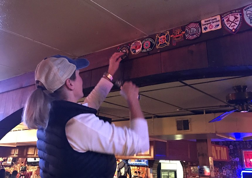 Olson adds a Grand Fire patch to the wall at Ott House.