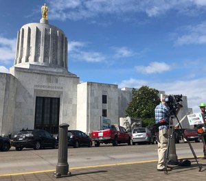 A TV reporter interviews self-employed logger Bridger Hasbrouck, of Dallas, Ore., outside the Oregon State House in Salem, Ore., on Thursday, June 20, 2019. (AP Photo/Gillian Flaccus)
