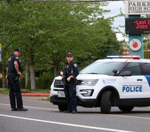 Police are positioned outside Parkrose High School Parkrose High School during a lockdown after a man armed with a gun was wrestled to the ground by a staff member (Dave Killen/The Oregonian via AP)