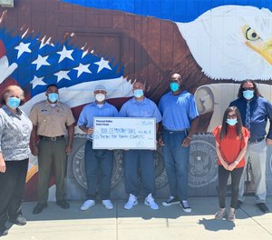 PVSP staff and Inmate Advisory Council representatives display donation for the Robb School Memorial Fund (Photo/ CDCR Press Office)