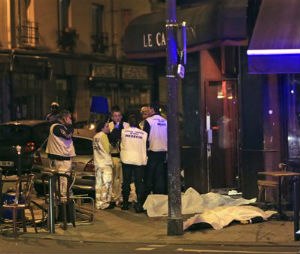 Medics attend the scene as victims lay on the pavement outside a Paris restaurant. Police report multiple terror incidents, including shootings, explosions and hostage taking, leaving many dead.