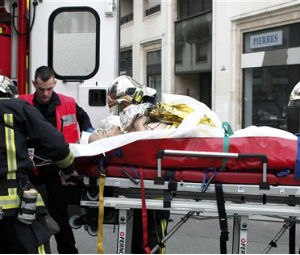 An injured person is transported to an ambulance after a shooting, at the French satirical newspaper Charlie Hebdo's office, in Paris, Wednesday, Jan. 7, 2015. (AP Photo/Thibault Camus)