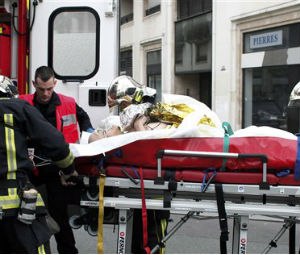 An injured person is transported to an ambulance after a shooting, at the French satirical newspaper Charlie Hebdo's office, in Paris, Wednesday, Jan. 7, 2015.