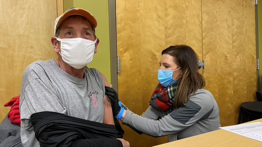Advanced Medical Transport Director of Innovation Kelly Walsh gives a vaccine shot to Terryl Brawner, a community servant and volunteer, as well as a local business owner.