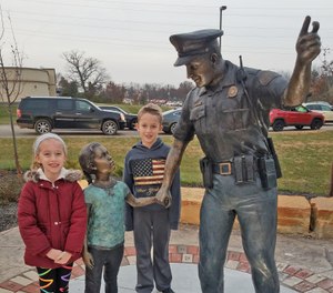 A bronze sculpture of a police officer and young girl is one of three sculptures by Ohio artist Tom Tsuchiya on display in Florence, Kentucky. (Photo/Exact Metrology)