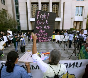 Protesters demonstrate outside the federal courthouse in Sacramento, Calif., where a judge heard arguments over the U.S. Justice Department's request to block three California laws that extend protections to people in the country illegally.