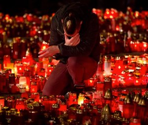 A man touches his forehead holding a candle outside the Colectiv nightclub in Bucharest, Romania, Friday, as people mark one week since a deadly fire started during a concert. (AP Photo/Vadim Ghirda)