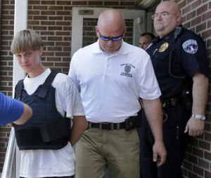 Charleston, S.C., shooting suspect Dylann Storm Roof, center, is escorted from the Shelby Police Department in Shelby, N.C., Thursday, June 18, 2015. Roof is a suspect in the shooting of several people Wednesday night at the historic The Emanuel African Methodist Episcopal Church in Charleston, S.C. (AP Photo/Chuck Burton)
