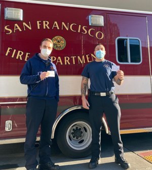 Firefighters display their COVID-19 vaccination cards.